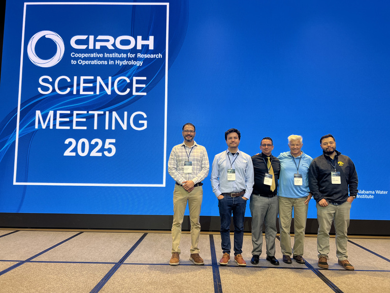 CIROH researchers stand on the stage and smile, at the CIROH 2025 Science meeting