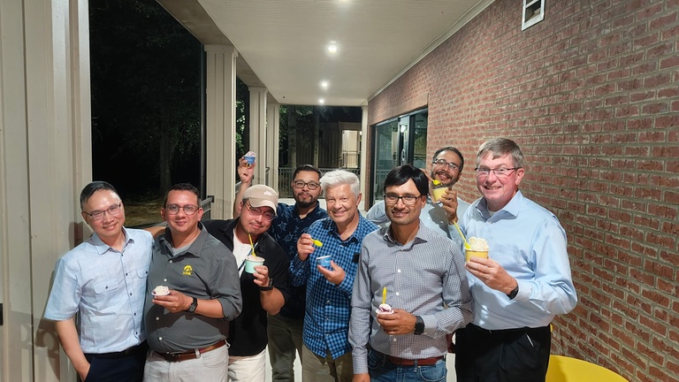 The CIROH group of researchers smiles and poses with their ice cream in a hallway